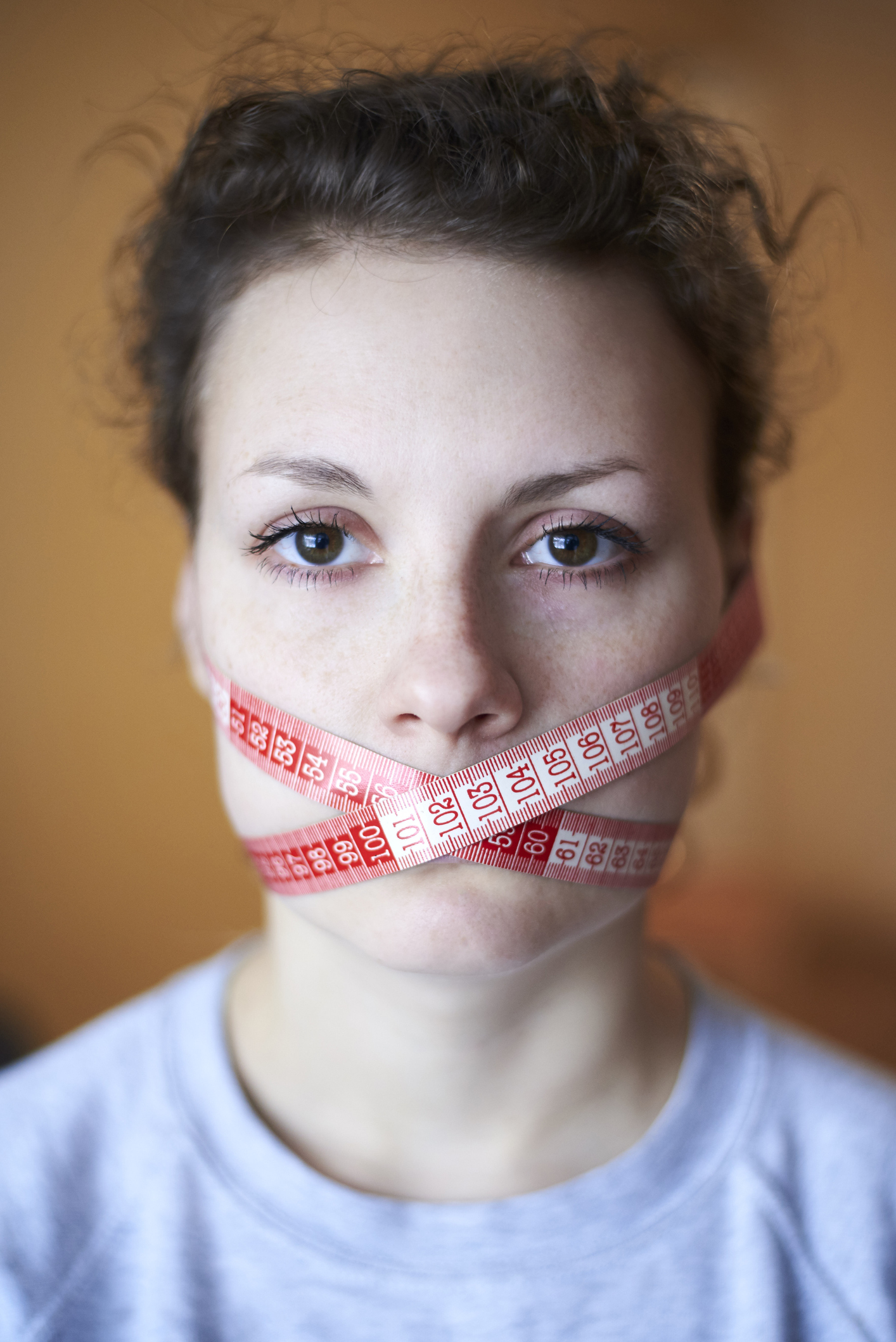 Sad woman with wrapped meter around face, topic of losing excess weight, diet and stress.